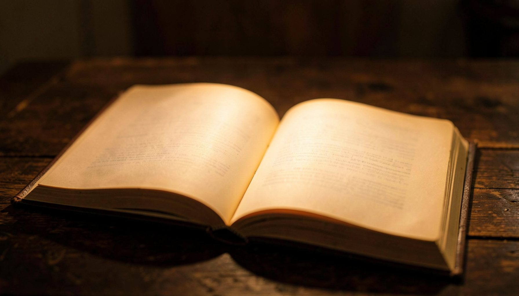 Livro aberto com páginas amareladas sobre uma mesa de madeira escura, iluminado por uma luz quente e suave que cria uma atmosfera íntima de leitura